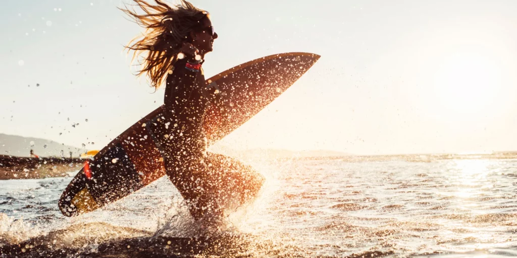 Mujer entrando al agua con una tabla de surf en una playa de Gran Canaria