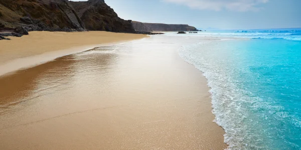 Imagen de una playa de arena dorada y aguas color turquesa en Canarias