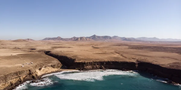 Playa natural de Esquinzo en Fuerteventura con arena dorada y mar abierto.