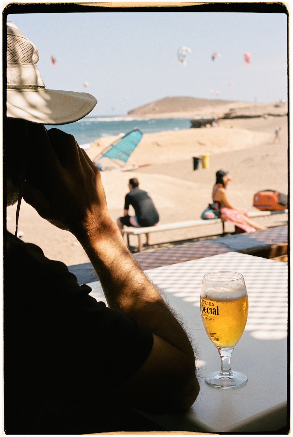 Persona relajándose en la playa de El Médano con una cerveza frente al mar.