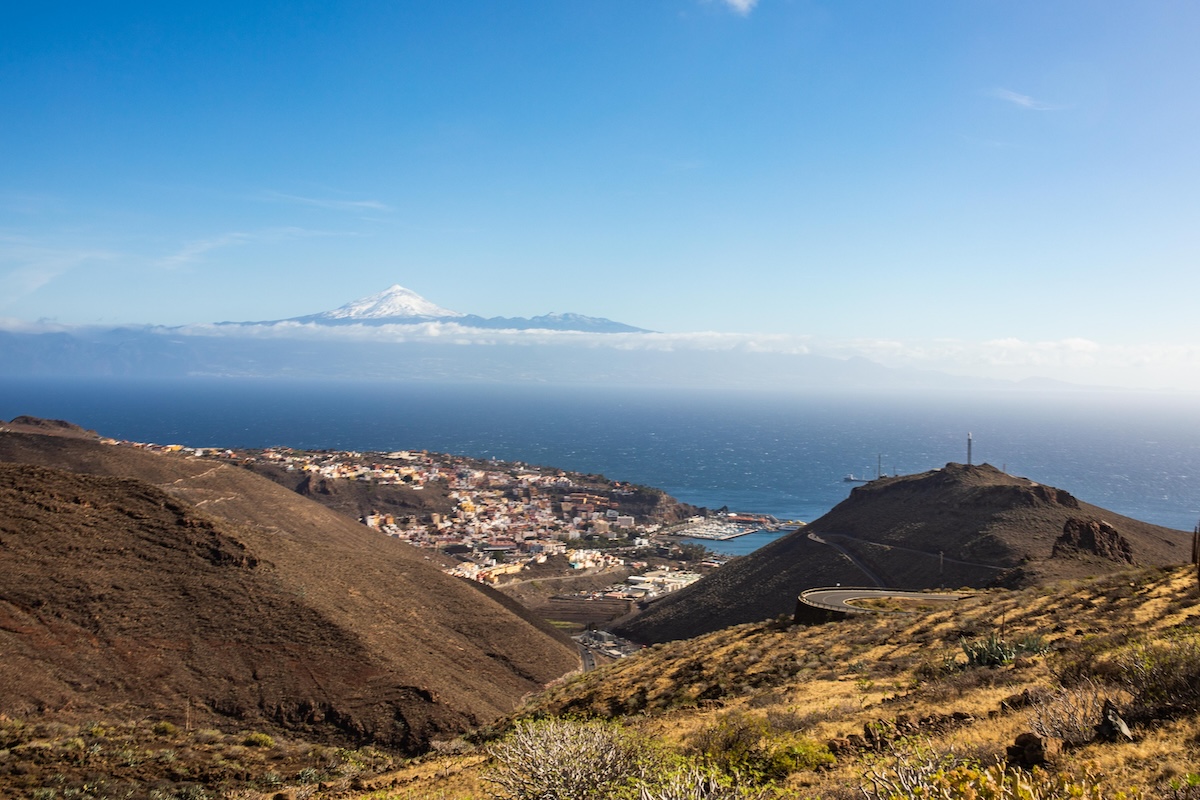 Ferry llegando al puerto de San Sebastián de La Gomera con la ciudad y las montañas al fondo en un día luminoso.