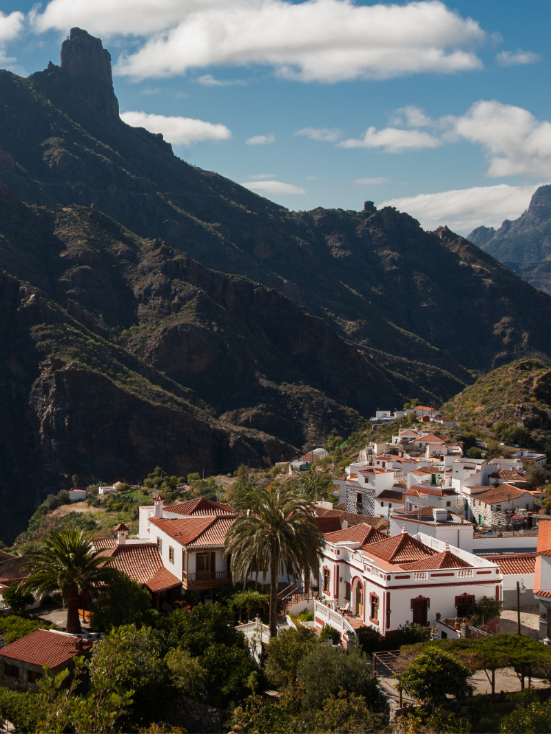 Paisaje de Tejeda con casas tradicionales, montañas volcánicas y el Roque Nublo al fondo en Gran Canaria.