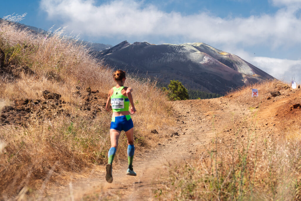 Corredora de El Reventón El Paso en carrera con un paisaje volcánico al fondo