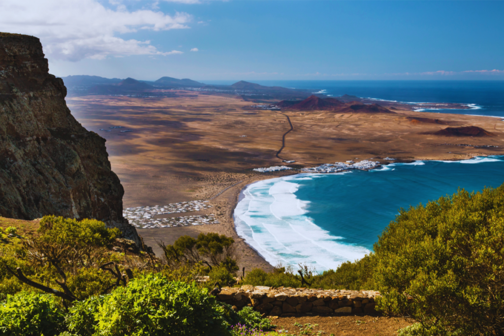 Vista de la playa de Famara, en Lanzarote, con olas rompiendo cerca de la costa