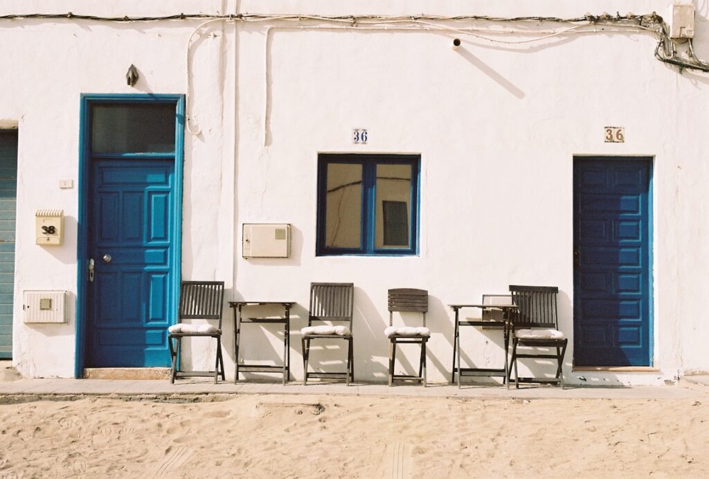 Fachada blanca de una casa en La Caleta de Famara con puertas y ventanas azules