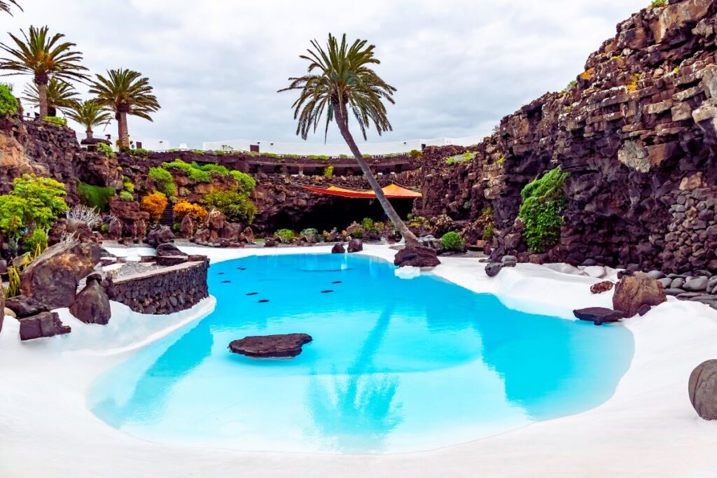 Piscina de los jameos del agua con palmera y paisaje volcánico