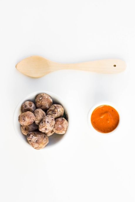 Un plato de papas arrugadas con mojo y una cuchara de madera