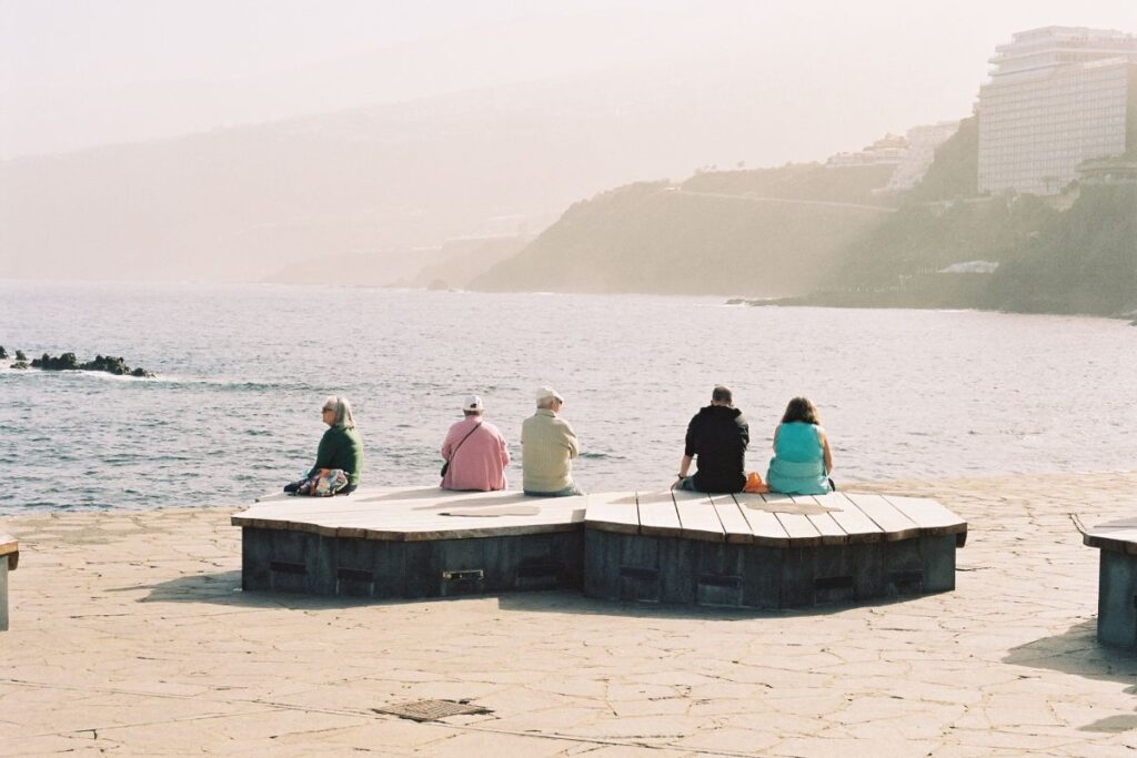 Paseantes descansando bajo el sol en el Puerto de la Cruz en Tenerife