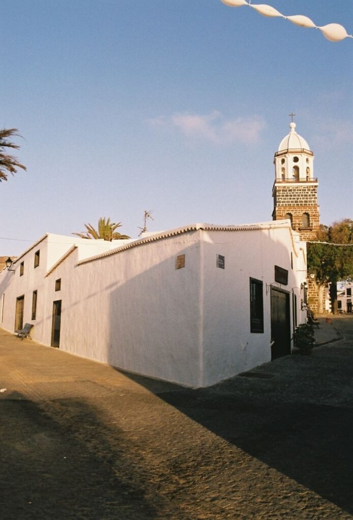 Fachada de casa blanca en Teguise con Iglesia de Nuestra Señora de Guadalope de fondo
