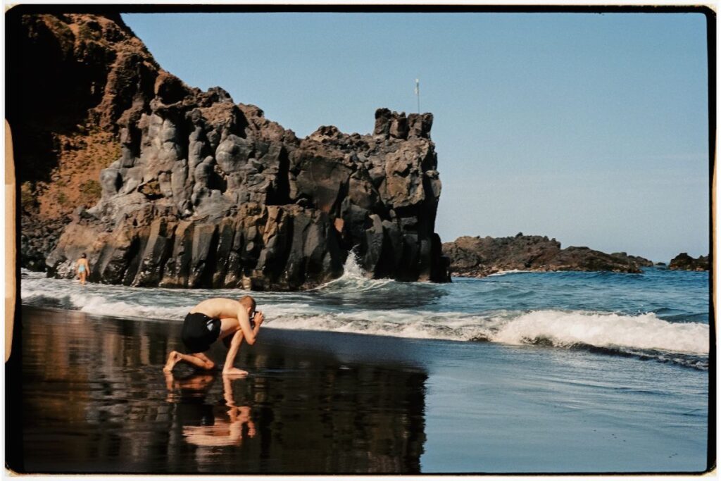 Fotógrafo en bañador tomando una fotografía de las olas entrando en la orilla