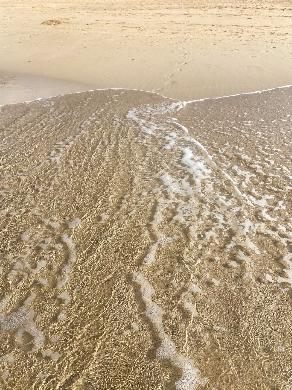 Agua movida por la marea en la orilla de la playa de Cofete