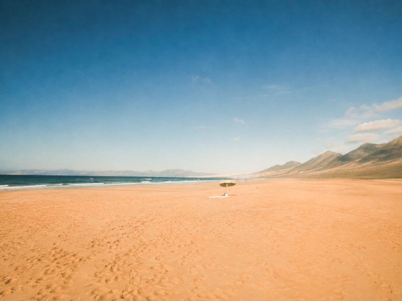 Sombrilla solitaria en medio de la arena en la playa de Cofete