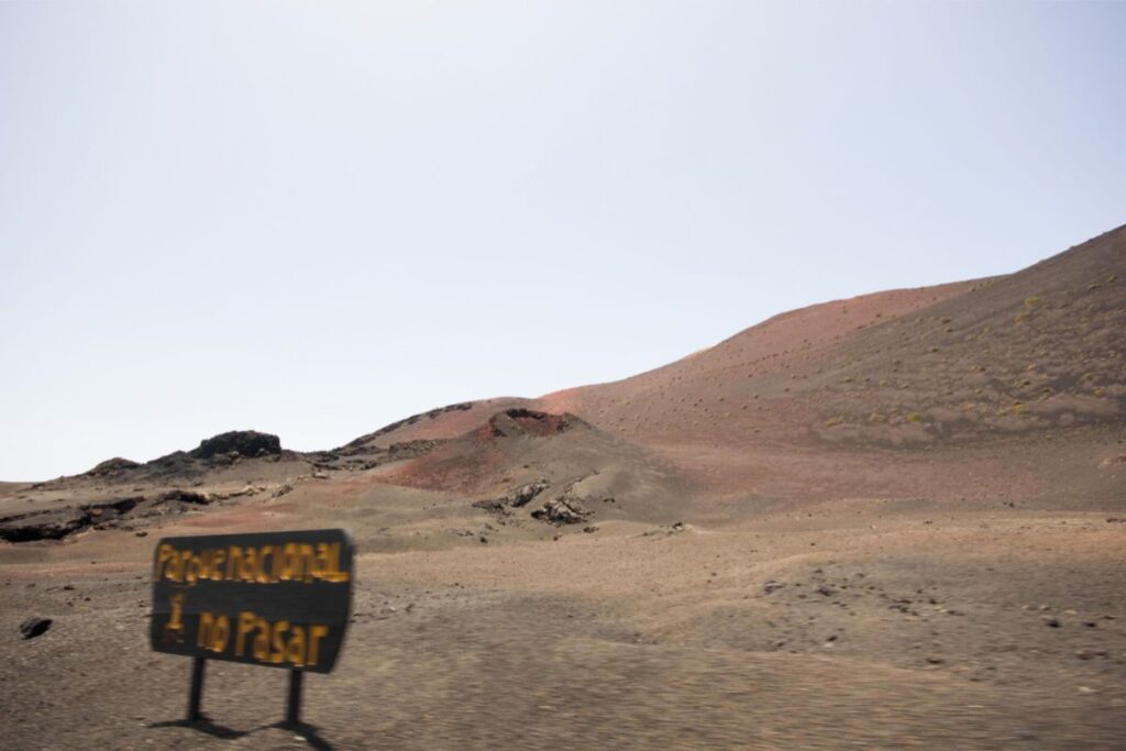 Cartel del Parque Nacional de Timanfaya con montañas volcánicas de fondo