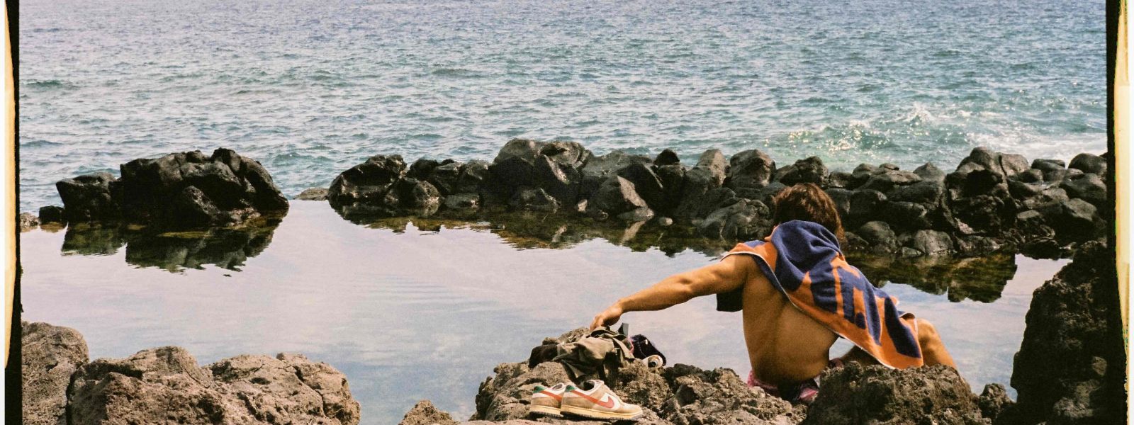 Hombre joven descansando junto a un charco en Canarias con su toalla